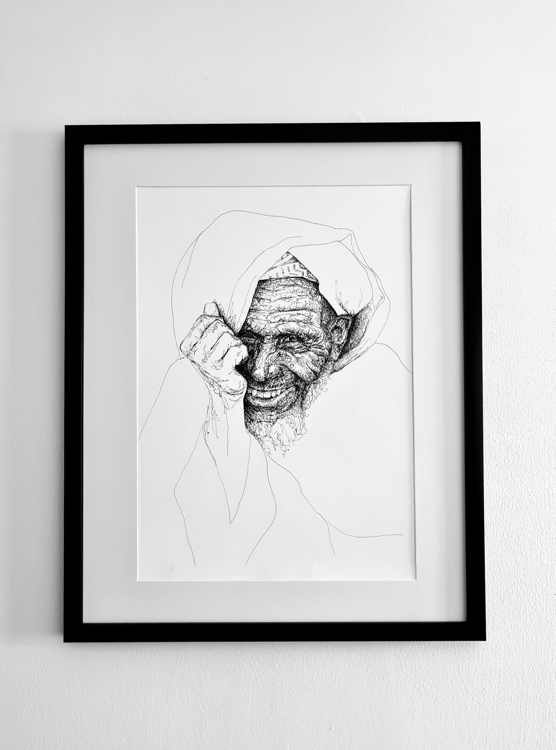 Framed black and white line drawing of a grinning man with his head propped on his palm. A portrait with a detailed face and minimalist drawn clothing